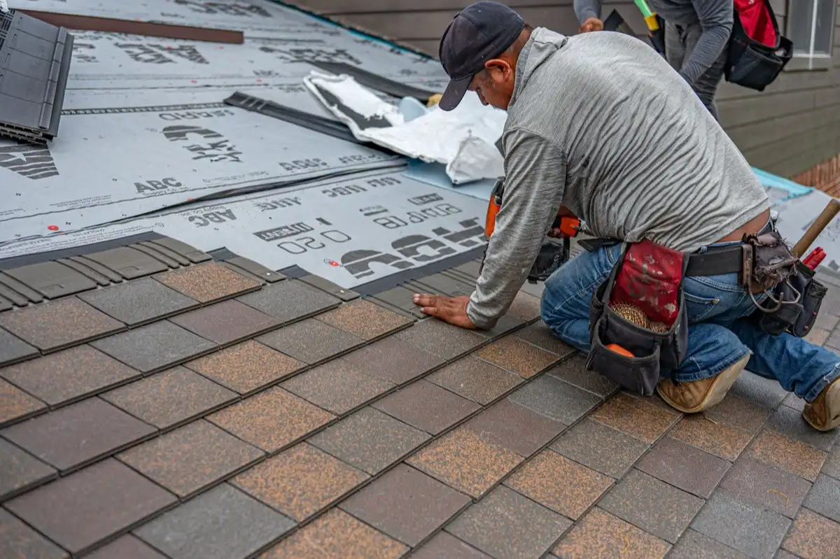 Roofing installer fastening shingles over new underlayment in Norman, OK